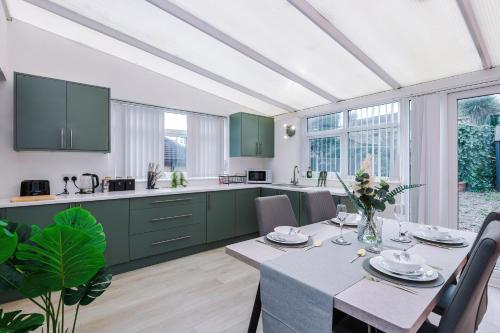 a kitchen with green cabinets and a table with chairs at The Lyme Lounge - Elegant & Contemporary 3BR Home - Sleeps 7 with Parking & WiFi - Ideal for Business Stays by Parydise Properties in Longport