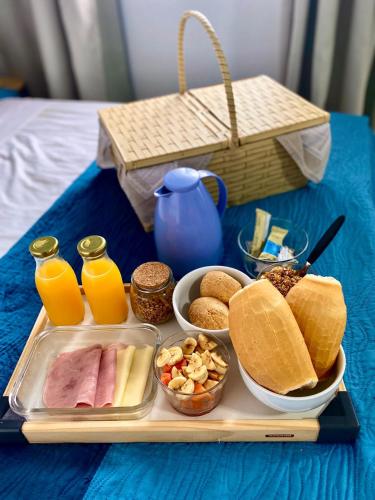 a tray with breakfast foods and orange juice on a bed at Pousada Loft São Chico - Exclusiva para casais in São Francisco do Sul