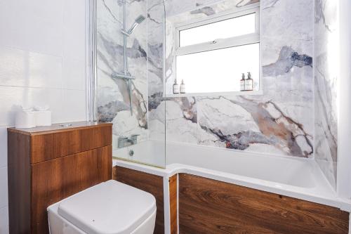 a bathroom with a tub and a toilet and a window at The Lyme Lounge - Elegant & Contemporary 3BR Home - Sleeps 7 with Parking & WiFi - Ideal for Business Stays by Parydise Properties in Longport