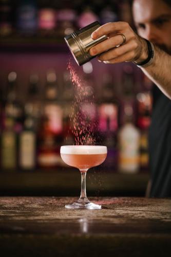 a person pouring a drink into a cocktail glass at Siberia Bar & Hotel in Aberdeen