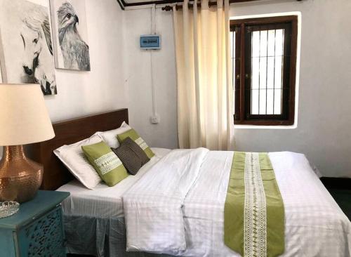 a bedroom with a bed with green and white sheets at Koshi's Country Cottage Ella in Ella