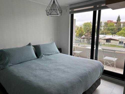 a bedroom with a bed and a large window at Departamento amoblado, centrico in Temuco