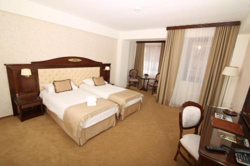 a hotel room with two beds and a desk at Hotel Carmen in Predeal