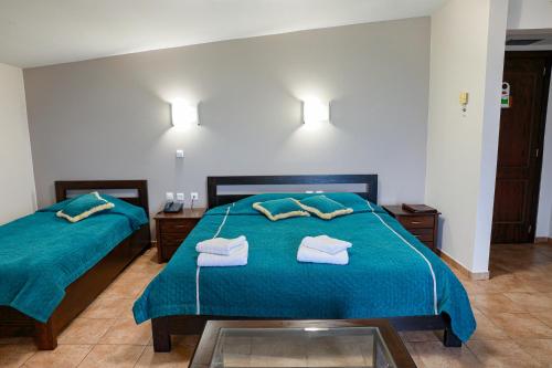a bedroom with two beds with blue sheets and towels at Le Chalet in Xanthi