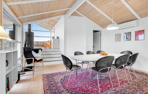 a dining room with a table and chairs on a rug at 5 Bedroom Stunning Home In Blokhus in Blokhus