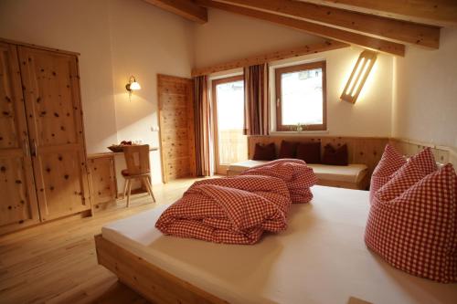 Habitación con cama con almohadas rojas y blancas. en Kinderbauernhof Ierzerhof, en Arzl im Pitztal