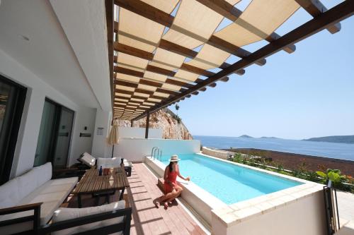 a woman sitting on a deck next to a swimming pool at Lures Hotel in Kalkan