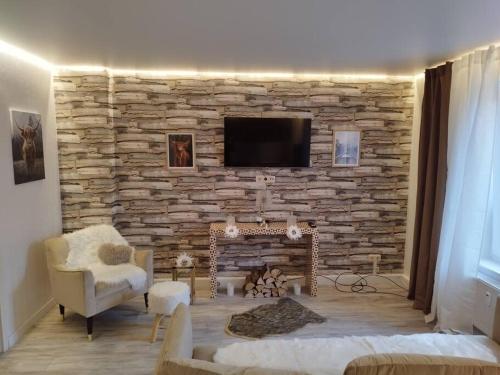 a living room with a stone wall with a tv at Gästewohnung -Chalet 1 bis 2 Pers in Magdeburg