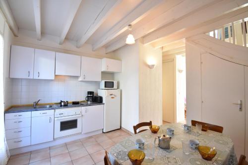 une cuisine avec une table et un réfrigérateur blanc dans l'établissement Clos du lac - Hossegor agréable villa patio au calme donnant sur deux terrasses est et ouest, à Soorts-Hossegor