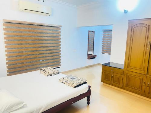 a bedroom with a bed and a dresser and a window at Mangosteen villa in Ernakulam