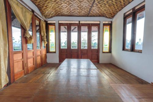 an empty room with wooden doors and windows at Artana Guest House By ARBA in Palayangan