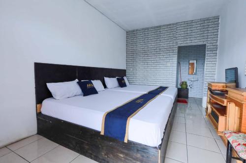 a large white bed in a room with a brick wall at Artana Guest House By ARBA in Palayangan