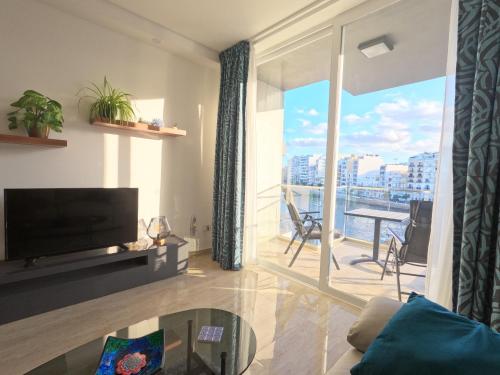 a living room with a flat screen tv and a balcony at Spinola Seaview Deluxe 1 Bedroom in St Julian's