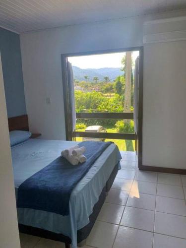 a bedroom with a bed with a large window at Cana Caiana Casa in Paraty