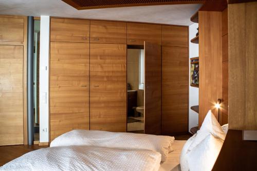 a bedroom with wooden walls and a bed with white sheets at Turm Chalet in Laces