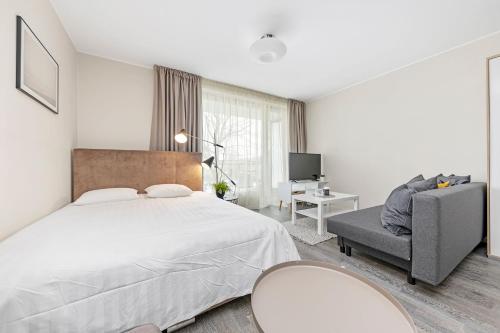 a bedroom with a large bed and a chair at Aisa Studio37 in Pärnu