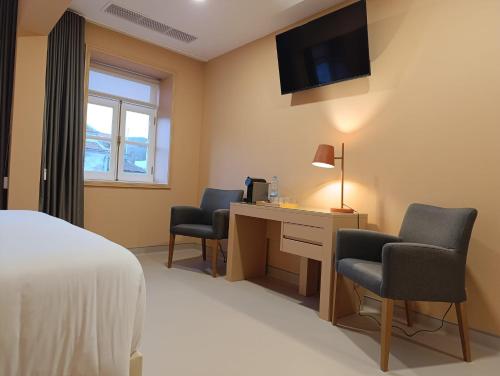 a hotel room with a bed and a desk and chairs at Hotel Margarida Da Praça in Viana do Castelo