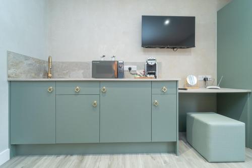 a kitchen with a counter with a tv on the wall at Bankton Rooms & Lodges in Livingston