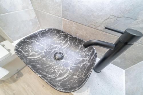 a metal sink in a bathroom with a marble wall at Bankton Rooms & Lodges in Livingston