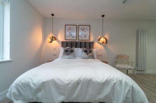a bedroom with a large white bed with two lights at Bankton Rooms & Lodges in Livingston