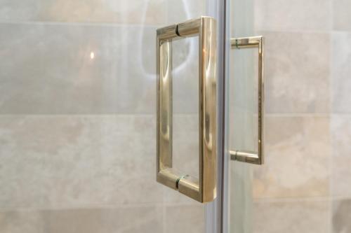 a glass shower door with a metal handle at Bankton Rooms & Lodges in Livingston