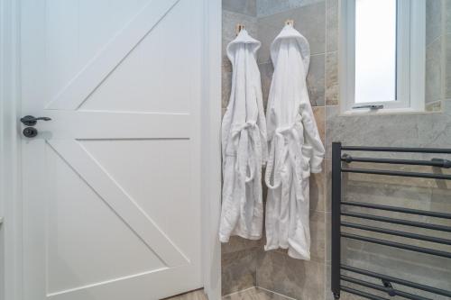 a group of white robes hanging on a wall in a bathroom at Bankton Rooms & Lodges in Livingston