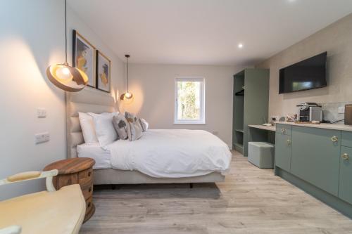 a bedroom with a white bed and a kitchen at Bankton Rooms & Lodges in Livingston