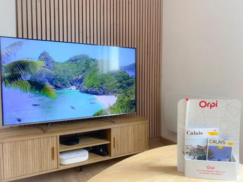 un téléviseur à écran plat posé sur un centre de divertissement en bois dans l'établissement Le Côte d'Opale, à Calais