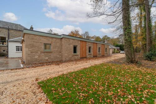 a stone house with a driveway in front of it at Bankton Rooms & Lodges in Livingston