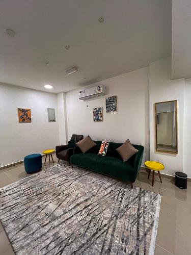 a living room with a green couch and a rug at Alhamra Horizons in Al Ḩamrāʼ