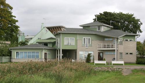 une grande maison avec deux bancs devant elle dans l'établissement Päeva Villa, à Haapsalu
