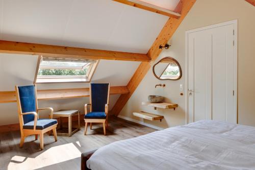 a bedroom with two blue chairs and a bed at Hof van Maldegem in Kortgene