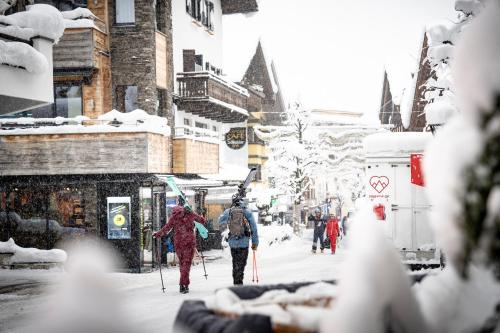 a group of people walking down a street in the snow at Quality Hosts Arlberg - AFOCH FEI - das Landhaus in Sankt Anton am Arlberg