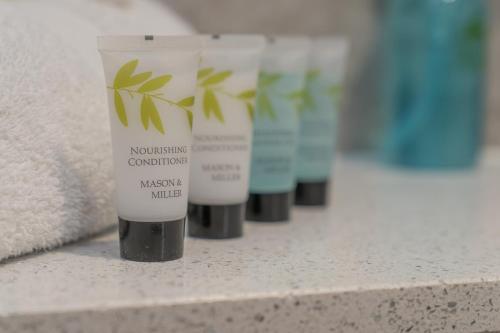a row of four bottles of nourishing cosmetics on a counter at Bankton Rooms & Lodges in Livingston