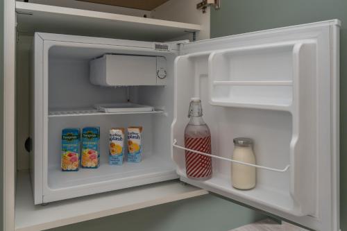 an open refrigerator with milk and drinks in it at Bankton Rooms & Lodges in Livingston