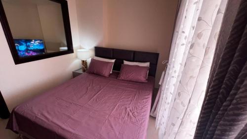 a bedroom with a bed with purple sheets and a mirror at Full sea view Studio high floor in Ras al Khaimah