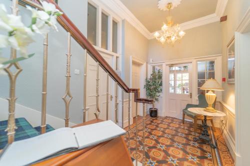 a hallway with a staircase and a chandelier at Bankton Rooms & Lodges in Livingston