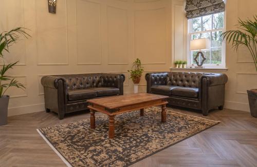 a living room with two leather couches and a coffee table at Bankton Rooms & Lodges in Livingston