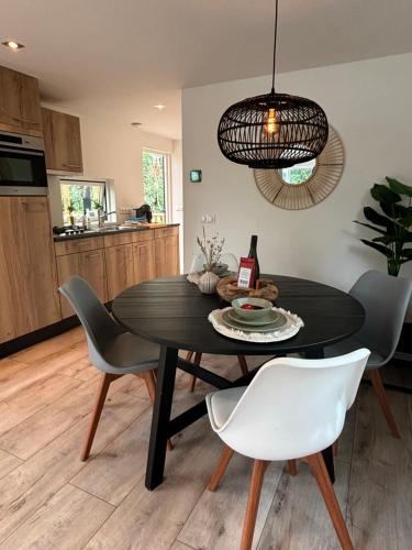 a dining room with a black table and chairs at Bosrijk chalet Veranda, Honden in Doornspijk