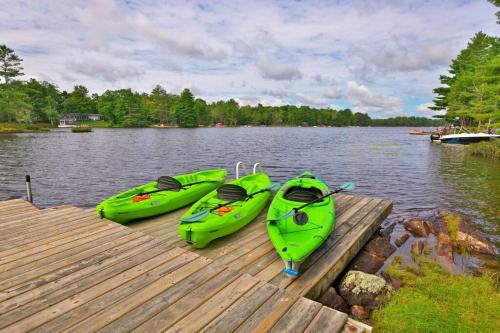 three kayaks sitting on a dock on a lake at Muskoka Retreat, Fire Pit, Games, Waterfront in Gravenhurst