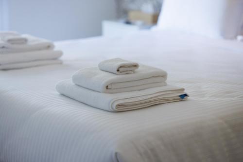a pile of towels sitting on top of a bed at The Palm Suites - Adults Only in Limassol
