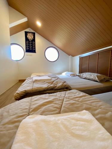 two beds in a room with two windows at Taka Onzen in Ban Khao Ket