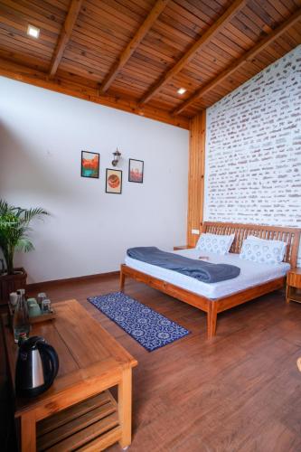 a bedroom with a bed and a wooden table at Shivoham Himalayan Resort in Almora