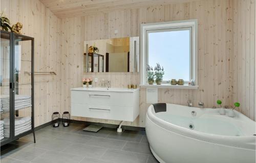 a bathroom with a tub and a sink and a mirror at Stunning Home In Væggerløse With Wifi in Marielyst