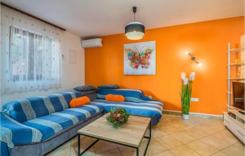 a living room with a blue couch and an orange wall at Stunning Apartment In Njivice With Wifi in Njivice