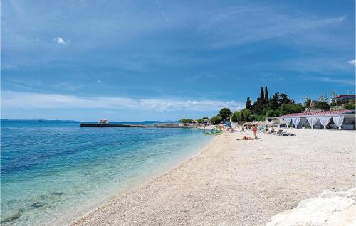a beach with people sitting on the sand and the water at Lovely Home In Podstrana in Podstrana