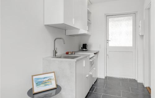 a white kitchen with a sink and a painting on the floor at 1 Bedroom Nice Apartment In Svaneke in Svaneke