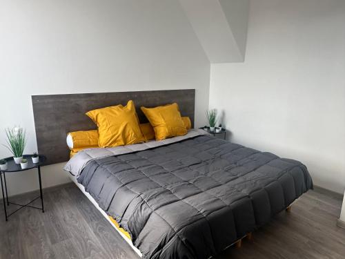 a bedroom with a large bed with yellow pillows at Appartement confortable Andrezieux Boutheon in Bouthéon
