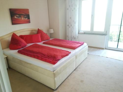 1 dormitorio con 1 cama grande con almohadas rojas en Gaestehaus Jagsttalblick Dürr, en Langenburg