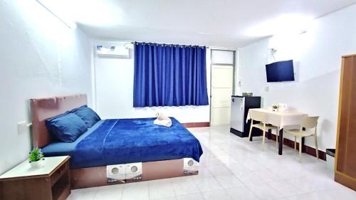 a bedroom with a blue bed and a table at Apartment near Central Festival Hatyai in Hat Yai